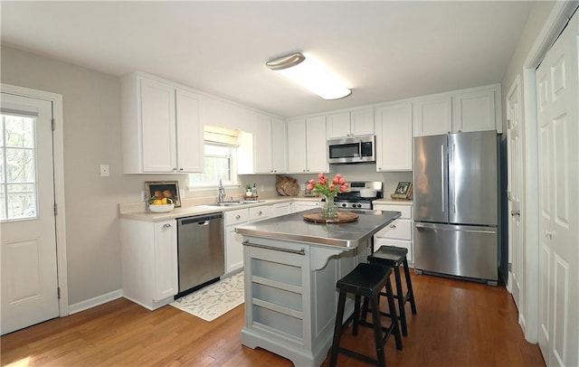 5415 Keithwood Dr, Cumming, GA 30040 - kitchen featuring a breakfast bar, white cabinets, stainless steel appliances, a sink, and wood finished floors