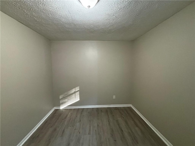 empty room with wood-type flooring and a textured ceiling