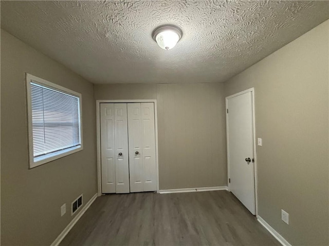 unfurnished bedroom featuring a closet, a textured ceiling, and hardwood / wood-style flooring