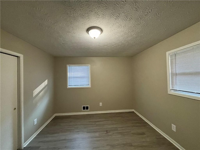 spare room featuring a textured ceiling and dark wood-type flooring