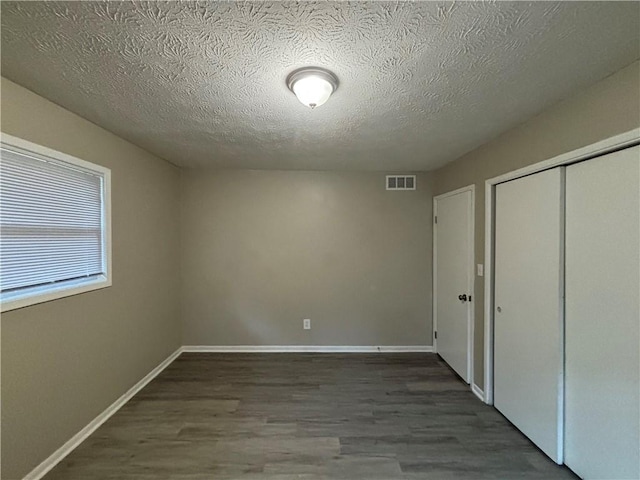 unfurnished bedroom featuring a closet, dark hardwood / wood-style flooring, and a textured ceiling