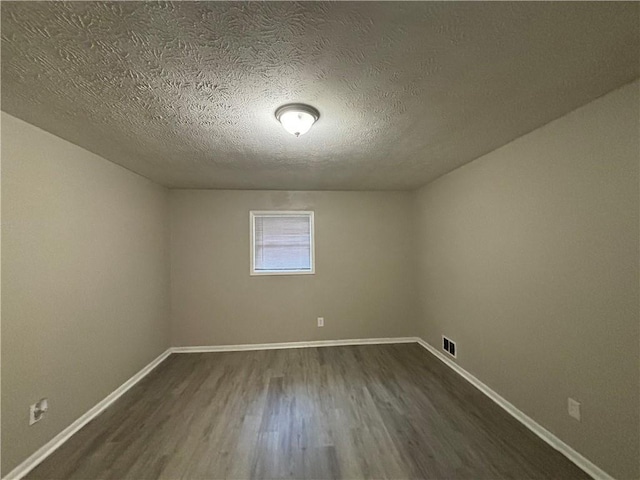 unfurnished room featuring a textured ceiling and dark hardwood / wood-style flooring