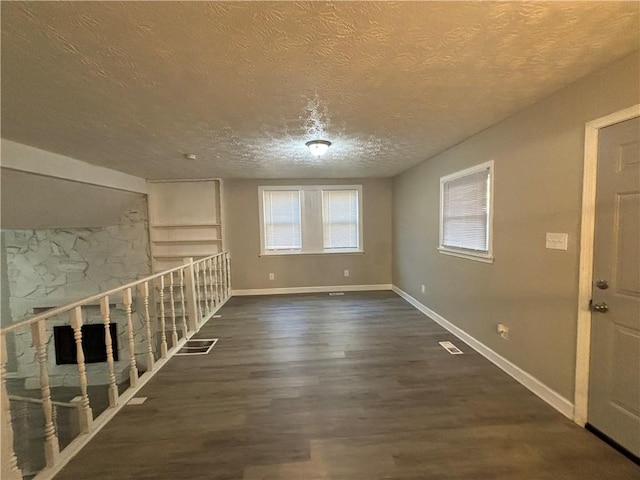 spare room featuring dark hardwood / wood-style flooring and a textured ceiling