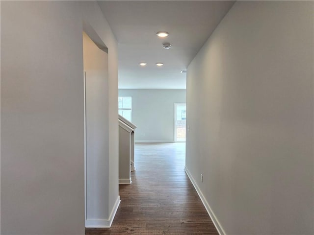 corridor with dark wood-style flooring and baseboards