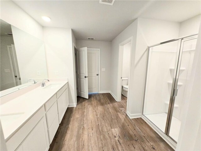 bathroom featuring a stall shower, visible vents, a sink, and wood finished floors