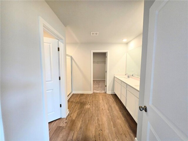 full bathroom featuring toilet, wood finished floors, a sink, baseboards, and a shower stall