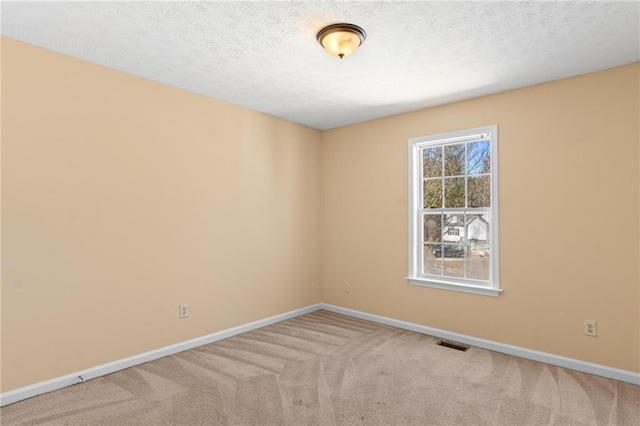 carpeted spare room with a textured ceiling, visible vents, and baseboards