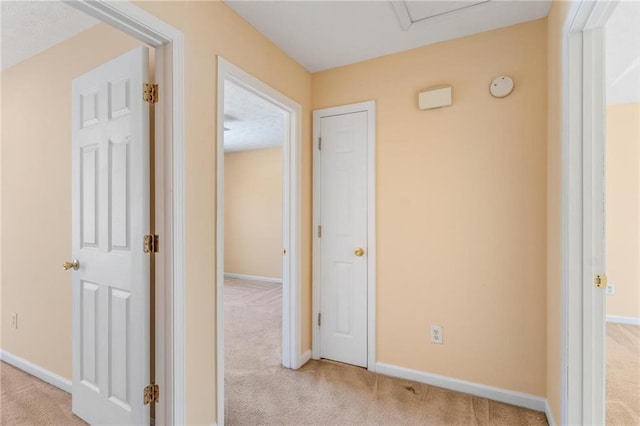 hall featuring light colored carpet and baseboards