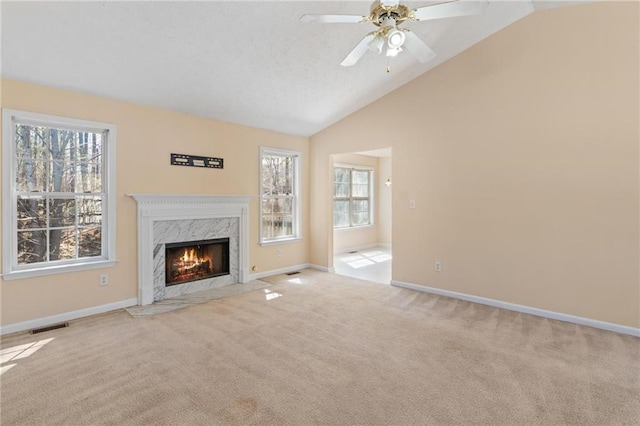 unfurnished living room featuring a high end fireplace, a wealth of natural light, carpet flooring, and lofted ceiling