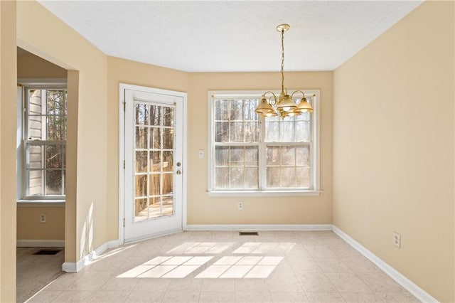 unfurnished dining area with an inviting chandelier, visible vents, light tile patterned floors, and baseboards