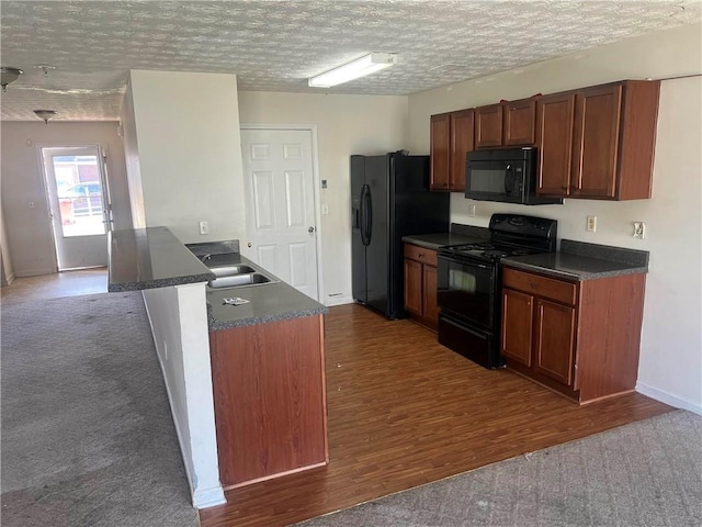 730 Georgetown Ln, Jonesboro, GA 30236 - kitchen with black appliances, dark countertops, dark wood-style floors, a peninsula, and a textured ceiling