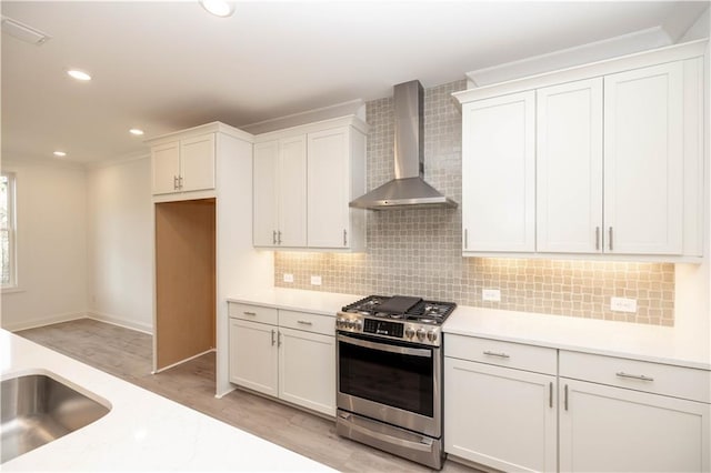 707 Dodd Ln N Unit 164, Buford, GA 30518 - kitchen featuring stainless steel gas range oven, wall chimney range hood, light wood finished floors, light countertops, and white cabinetry