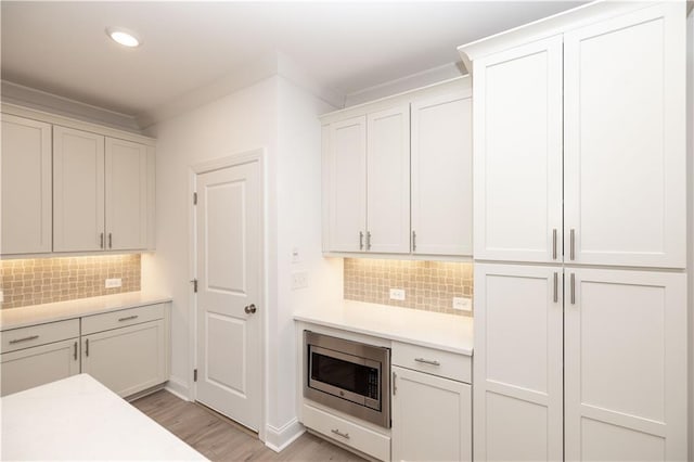 707 Dodd Ln N Unit 164, Buford, GA 30518 - kitchen featuring stainless steel microwave, light countertops, tasteful backsplash, light wood-style flooring, and recessed lighting