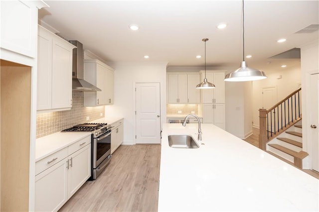 707 Dodd Ln N Unit 164, Buford, GA 30518 - kitchen featuring stainless steel gas range oven, wall chimney exhaust hood, a sink, backsplash, and white cabinetry