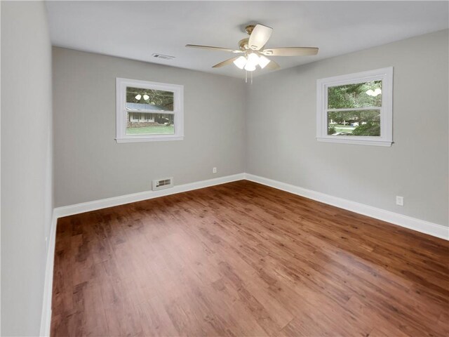 empty room with a wealth of natural light, ceiling fan, and hardwood / wood-style floors