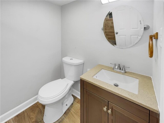 bathroom with wood-type flooring, vanity, and toilet