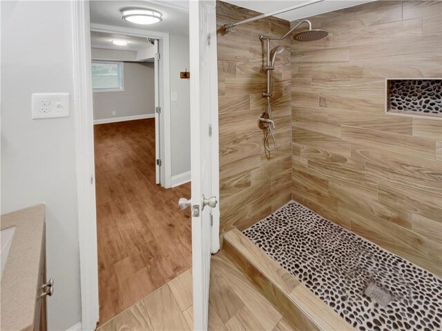 bathroom with tiled shower, vanity, and hardwood / wood-style flooring