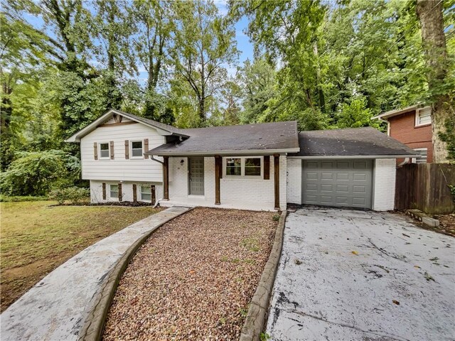 tri-level home featuring a garage, a front yard, and covered porch