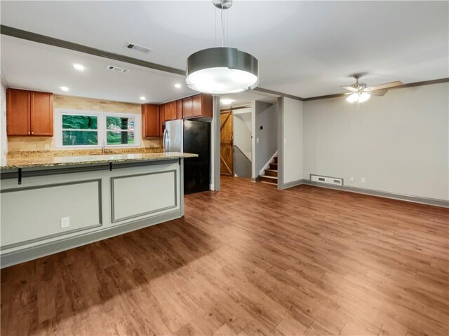 kitchen with pendant lighting, light wood-type flooring, tasteful backsplash, ceiling fan, and stainless steel fridge