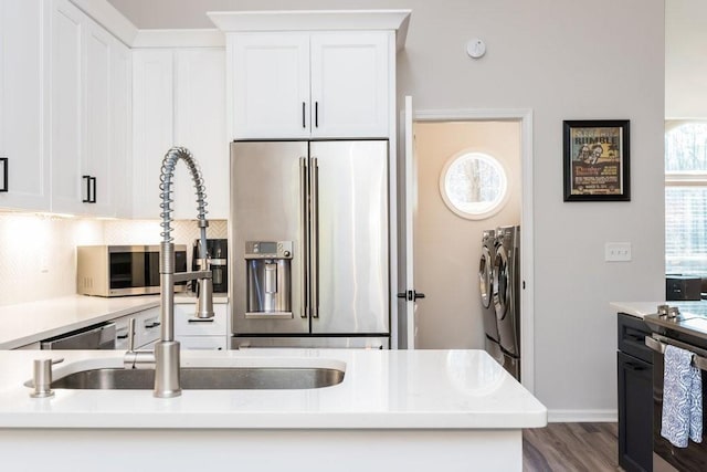 6060 Carriage Dr, Cumming, GA 30028 - kitchen with stainless steel appliances, washer and dryer, white cabinetry, decorative backsplash, and light countertops