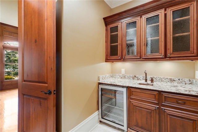 bar featuring sink, light stone countertops, ornamental molding, and beverage cooler