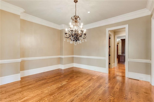 empty room featuring a chandelier, wood-type flooring, and ornamental molding