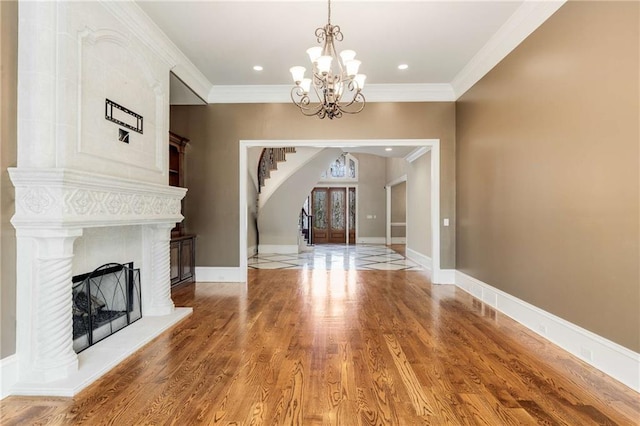 unfurnished living room with a notable chandelier, wood-type flooring, ornamental molding, and french doors