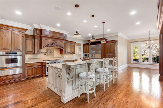 kitchen with light stone countertops, a kitchen breakfast bar, pendant lighting, built in appliances, and a center island with sink