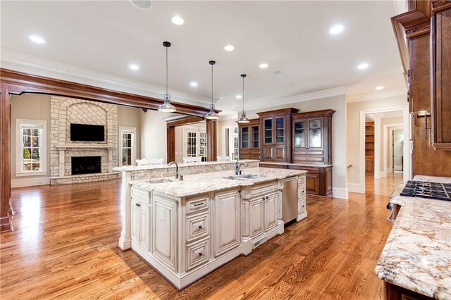 kitchen featuring sink, hanging light fixtures, crown molding, stainless steel dishwasher, and a large island