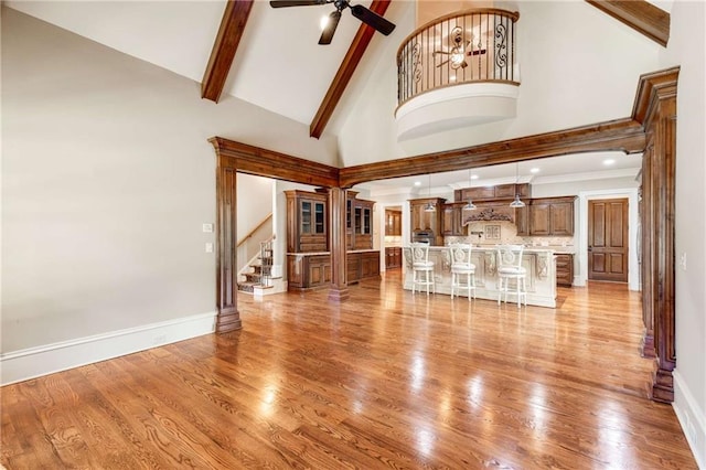 unfurnished living room with light hardwood / wood-style floors, high vaulted ceiling, and ceiling fan