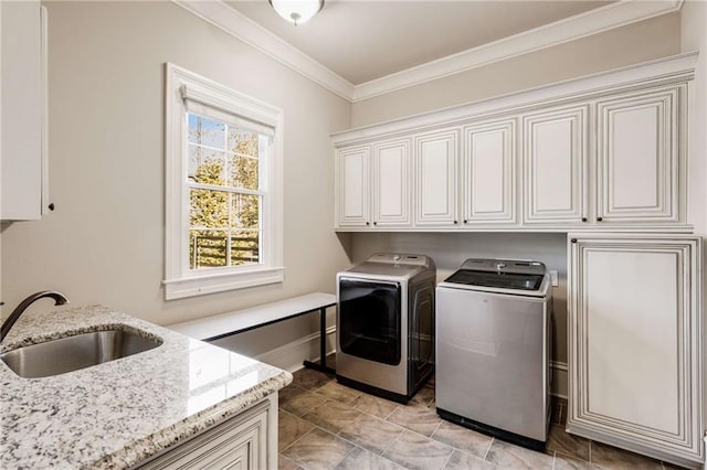 clothes washing area with cabinets, washer and clothes dryer, crown molding, and sink