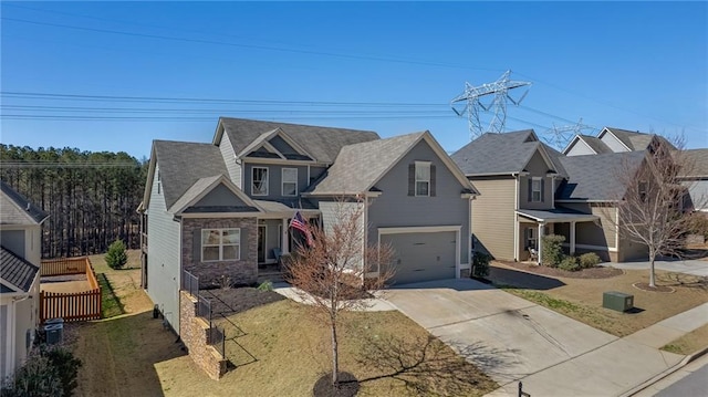 craftsman-style house featuring driveway, stone siding, fence, a front yard, and an attached garage