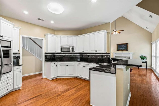 2709 Windrush Dr, Buford, GA 30518 - kitchen featuring stainless steel appliances, a sink, a peninsula, light wood finished floors, and white cabinetry