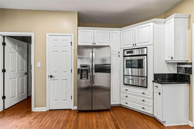 2709 Windrush Dr, Buford, GA 30518 - kitchen featuring stainless steel appliances, a warming drawer, white cabinets, wood finished floors, and dark stone countertops