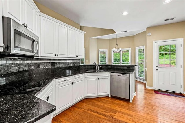 2709 Windrush Dr, Buford, GA 30518 - kitchen featuring stainless steel appliances, a sink, a peninsula, a chandelier, and white cabinetry