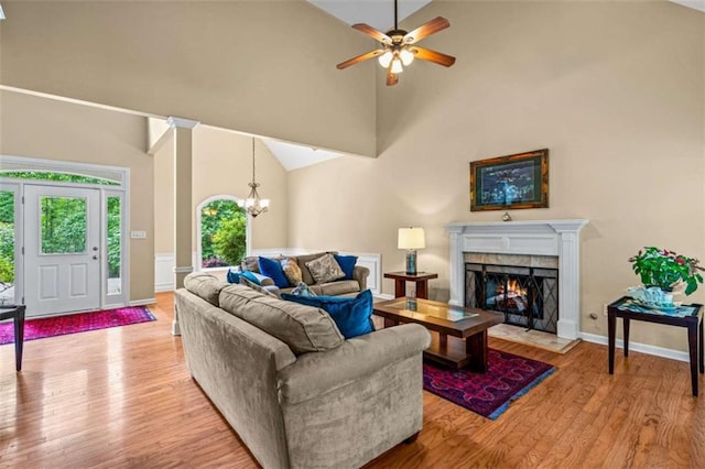 2709 Windrush Dr, Buford, GA 30518 - living room featuring high vaulted ceiling, light wood finished floors, a premium fireplace, a ceiling fan, and a chandelier