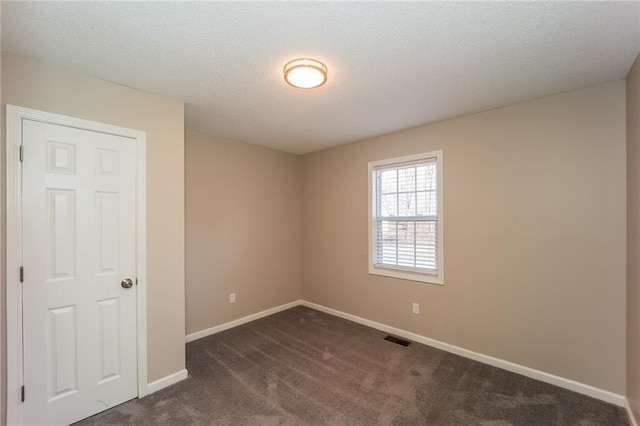 empty room featuring dark colored carpet and a textured ceiling