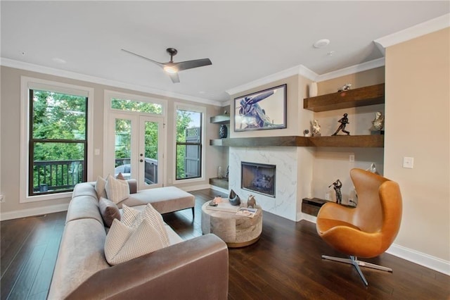 living room with a fireplace, ornamental molding, ceiling fan, dark wood-type flooring, and french doors