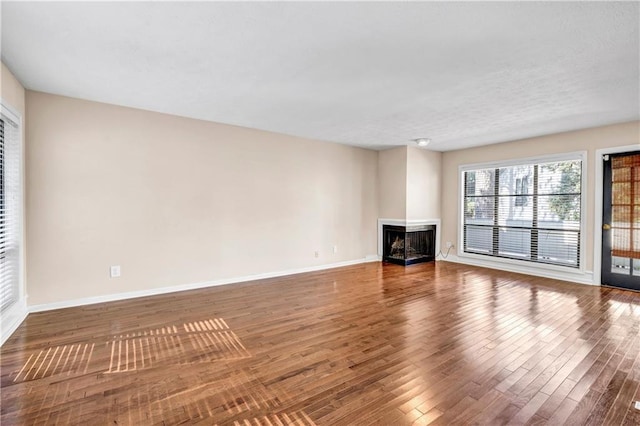 unfurnished living room featuring a multi sided fireplace and hardwood / wood-style flooring