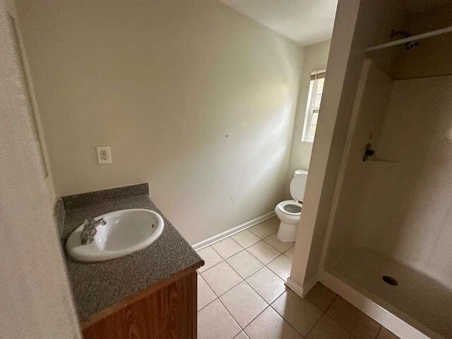 bathroom featuring tile patterned floors, vanity, toilet, and a shower