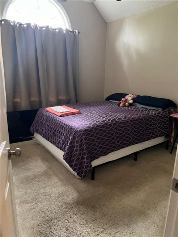 bedroom with carpet flooring, vaulted ceiling, and multiple windows