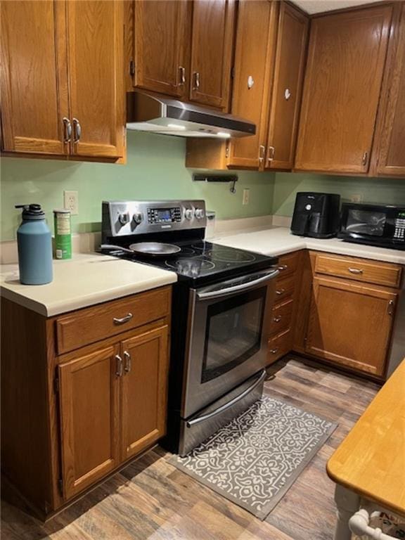 kitchen featuring stainless steel electric range oven and hardwood / wood-style flooring