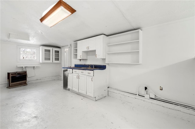 kitchen featuring heating unit, sink, and white cabinets