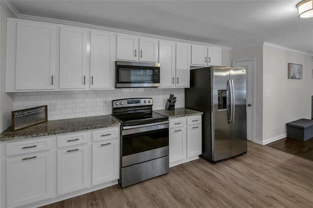 kitchen featuring appliances with stainless steel finishes, light wood-type flooring, white cabinetry, and dark stone counters