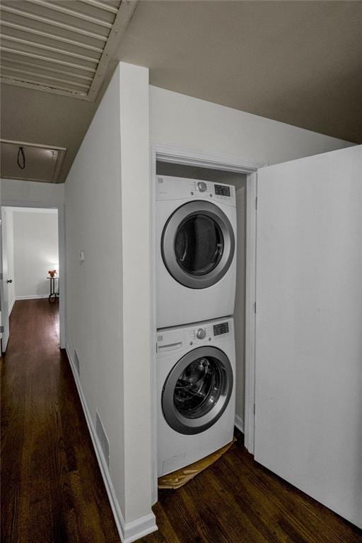 washroom with stacked washer and dryer and dark wood-type flooring