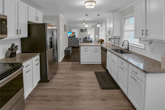 kitchen featuring sink, kitchen peninsula, light hardwood / wood-style floors, white cabinets, and appliances with stainless steel finishes