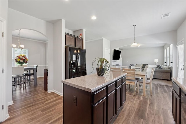 81 Birch River Pointe, Dallas, GA 30132 - kitchen featuring black fridge, arched walkways, dark brown cabinets, wood finished floors, and decorative light fixtures