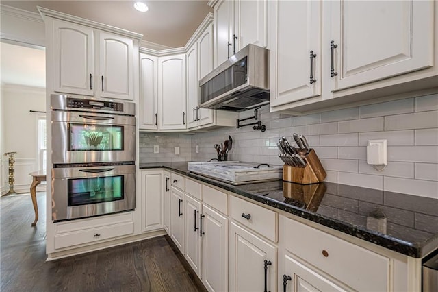 113 Gold Bridge Xing, Canton, GA 30114 - kitchen featuring appliances with stainless steel finishes, ornamental molding, white cabinetry, dark wood-style flooring, and dark stone countertops