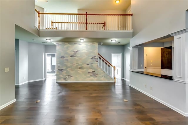 unfurnished living room with a high ceiling and dark wood-type flooring