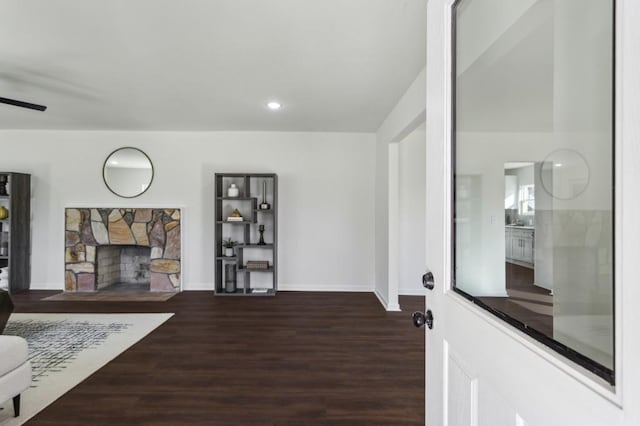 living area with baseboards, ceiling fan, wood finished floors, a stone fireplace, and recessed lighting